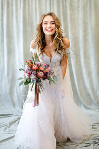 年轻的caucasian新娘站在摄影棚 与鲜花背景图片