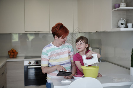 一厨二卫母亲和女儿在厨房里玩耍和准备钱财闲暇孩子们父母微笑午餐妈妈食物女孩药片喜悦背景