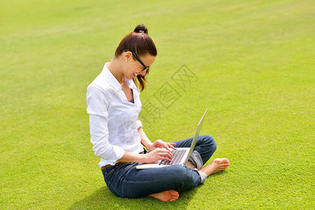 随意草公园里有笔记本电脑的妇女微笑场地成人学习快乐商业喜悦闲暇互联网生活背景