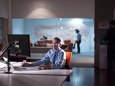 计算机商人在暗办公室从事计算机工作的男子商业桌子职业技术桌面商务监视器屏幕程序员经理背景