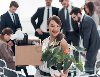 拥有办公室背景上个人物品的年轻青年雇员 在工作单位公司同事团队微笑盒子女士男人人士工作会议现代的高清图片素材