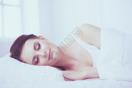 年轻美丽的女人躺在床上女士唤醒卧室女性图片