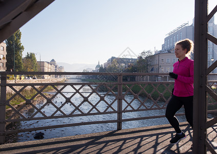 运动女运动员早上慢跑日出跑步成人卷曲慢跑者日落活力公园城市人行道图片