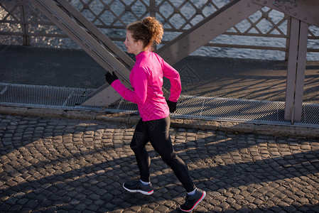 运动女运动员早上慢跑成人女孩活力公园人行道日落女士跑步卷曲慢跑者图片