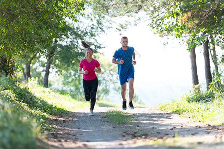 森林慢跑夫妻在乡村路上慢跑时享受健康的生活方式 在农村公路上游骑竞赛男性女性娱乐太阳公园日光晴天训练锻炼背景
