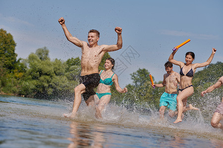 一群快乐的朋友在河边玩乐学生青年团体跳跃男人跑步游泳膀子派对女士图片