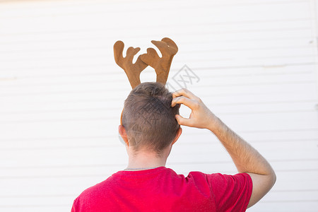 额头长着鹿角圣诞节 假期和人们的概念 — 一个长着鹿角的男人的头 男人挠头 后视背景