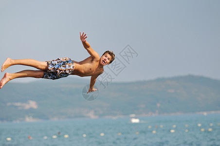 男孩跳海乐趣男人热带海滨青年旅行天空运动孩子技巧背景