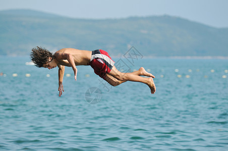 男孩游泳男孩跳海海岸海滨波浪天空闲暇技巧活力自由地平线海洋背景