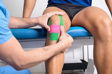 弹力绷带生理治疗师在男性病人膝盖上应用了动脉胶带 Kinesilogy 物理治疗 康复概念扭伤身体运动机肌内效运动药品治疗师胶带职业成人背景