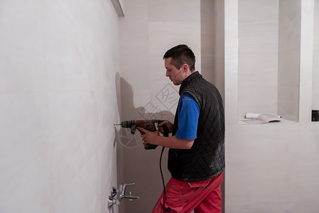 白洞建筑工人在卫生间钻探洞孔男人职业钻头承包商浴室维修木匠工作房子工具背景