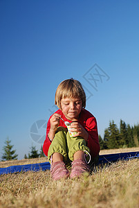 在户外吃健康食物的可爱小女孩喜悦天空快乐生活青年女性幸福活力野餐闲暇图片