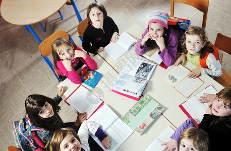 书和问在学校课堂上与教师在一起的快乐儿童同学孩子们学习手势团体童年桌子小学生女孩瞳孔背景