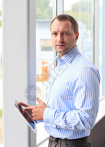 一名年轻商务人士在办公室的密切关头 用现代平板电脑做他的工作图片