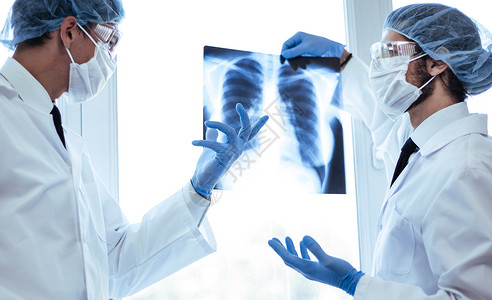 肺部研究近距离接近 戴防护面罩的科学家在看肺部X光片技术症状成人测试疾病从业者职业讨论眼镜x光背景