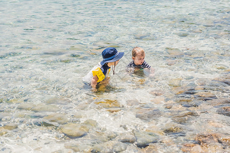 坦率的乐趣两个男孩在海上游泳背景