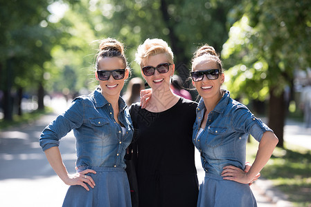 三个年轻美女的肖像 戴墨镜的太阳镜乐趣女士头发友谊成人青年团体情绪公园双胞胎背景图片
