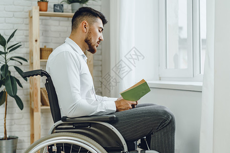 残疾人在轮椅上阅读室内书籍的残疾男子学生工作房子男人放松残障人士思维学习闲暇背景图片