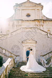 新娘和新郎站在古教堂附近的石头阶梯上背景图片