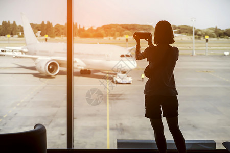 女孩拍了飞机的照片女性手机旅行飞机场商业乘客旅游日落工人互联网图片