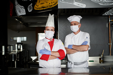 厨师带口罩在冠状病毒新常态概念下 一群厨师戴着防护医用口罩和手套站在餐厅的厨房里烹饪团队服务男性混血成人卫生男人疾病帽子背景