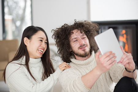 女士壁炉在壁炉前使用平板电脑的多种族夫妇在壁炉前成人男人头发网络奢华冲浪思考夫妻微笑女孩背景