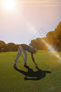 高尔夫球手把球打在Tee上娱乐帮助蓝色贮存草地活动夫球天空力量推杆图片