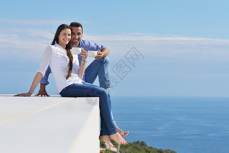 快乐的年轻浪漫情侣 有乐趣放松牙齿男人逃离房子保险女孩阳台幸福生活海洋图片