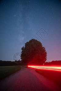 简约十字星光树上的银河边有红色的灯光 在星星之夜骑着自行车背景