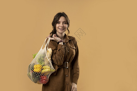 可商用花边零废物概念 一个小女孩肩上扛着一个装有杂货的纺织网状生态袋 没有塑料的概念 零浪费 无塑料 可持续的生活方式背景
