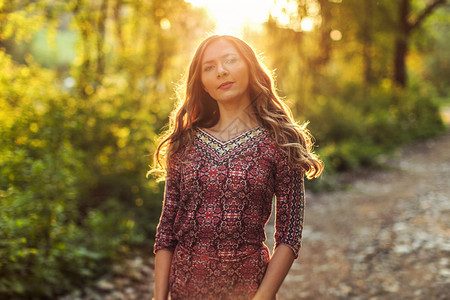 年轻女性穿着衣服 在日落时的森林背光下图片