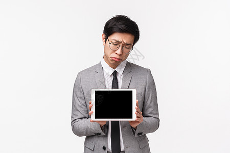 阴郁 心烦意乱的亚洲年轻男子在网上比赛中失利 没有获奖 表现不佳 做鬼脸和叹气沮丧的腰部肖像 显示数字平板电脑屏幕背景