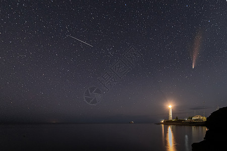 夜下灯塔夜晚夜空中白色灯塔上新颖彗星的全景场景星系天空行星天文海滩海洋宇宙蓝色粮食城市背景