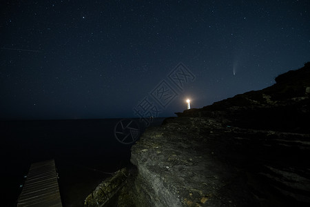 在海滩的夜空中 白色灯塔上空的新颖彗星的风景高清图片