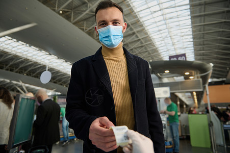 在国际机场出发前接受测试后 戴着防护性医用口罩的英俊年轻人收到二维码 大流行期间的安全飞行和旅行背景图片