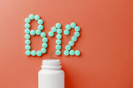 钴胺素红色基质上的维生素B12 从白罐里倒出来木头药片食物地面健康颗粒治疗制药瓶子药店背景