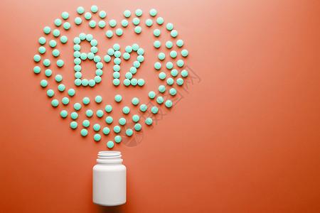 钴胺素B12维生素 以心脏的形状 在红色基质上 从白色罐子里倒出来食物营养药片颗粒制药药店标签托盘药物治疗背景