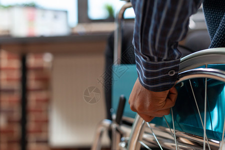 初创员工手持轮椅轮缘在办公桌前移动的特写图片
