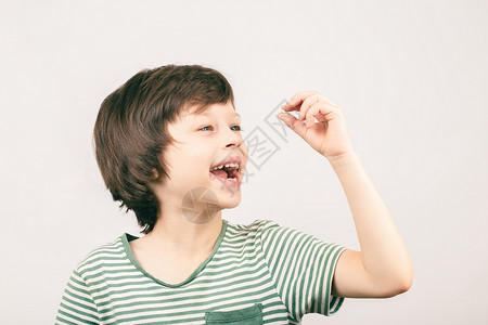 第一颗原子弹年轻男孩看着他第一颗输掉的奶牙健康牙科男性牙齿微笑牛奶童年孩子快乐乳牙背景