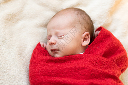 顶视图肖像生命第一天新生儿可爱睡着的婴儿在圣诞老人的帽子包裹在红色尿布地毯在白色花环背景 圣诞快乐 新年快乐 婴儿 童年 冬天的背景图片