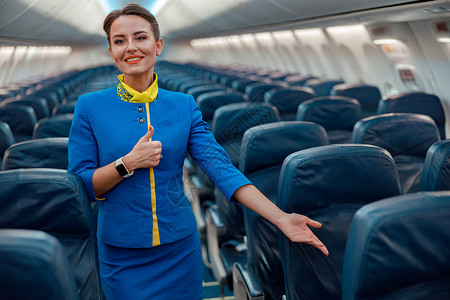 指着飞机舱乘客座椅微笑的空姐们成人运输走道空气工人座位椅子快乐商业服务员背景图片