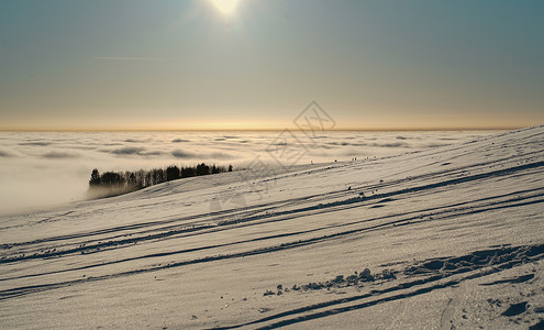 富氢水杯冬季在雪地滑雪 滑雪板或雪橇上放松的概念 日落时在德国黑森州山的夕阳下行走全景冒险阳光假期旅游季节风景环境爬坡天空背景