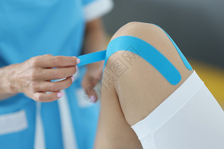 生理治疗师在客户膝盖上贴有运动生物学蓝色胶带图片