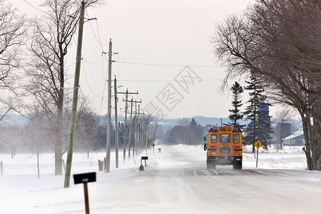 下雪邻里校车在一条乡村公路上行驶 有雪地漂浮和冬季吹雪背景