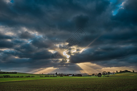 太阳的光线穿透了农地上的云丘陵农场地标假期日落自由天气天空草地旅行图片