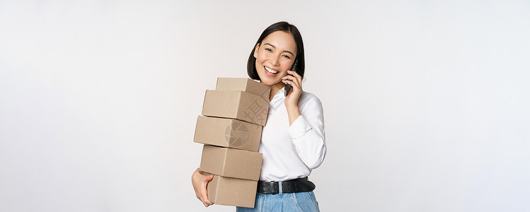 买一送二年轻亚洲女商务人士携带送货箱时接听电话的图像 以白色背景出现 照片来自工作室女士管理人员售货员人士送货女性商业冒充商品背景