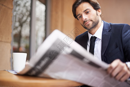 今日商业界发生的事 一个年轻商务人士 在咖啡店户外看报纸的书了 他是个大生意人背景图片