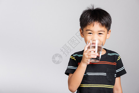 饮料与男孩可爱的小可爱男孩56岁 笑着从玻璃里喝清水 在摄影棚拍摄的隔绝镜头中男生孩子童年液体婴儿食物饮料白色背景