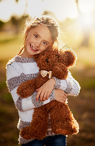 泰迪是她初恋的真爱 一个可爱小女孩的肖像 在外边玩耍时拥抱她的泰迪熊图片