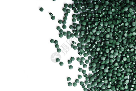 Spirulina的蔬菜维生素散布在白种背景上食物胶囊海藻藻类排毒叶绿素粉末药品饮食营养背景图片